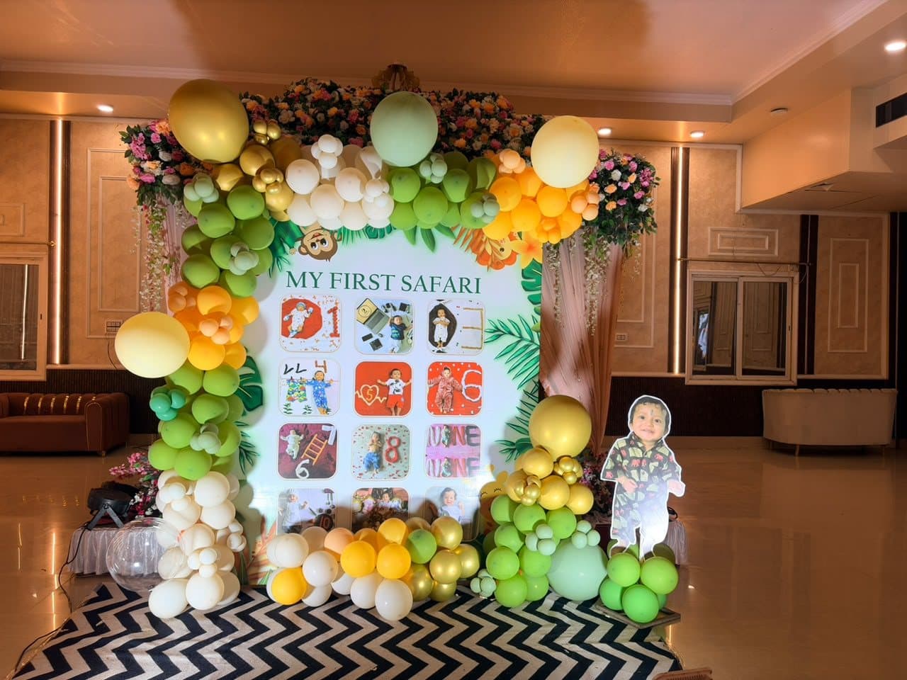 Jungle-themed milestone photo board reading My First Safari framed by green, yellow and white balloons